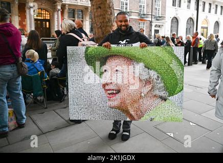London UK 19th September 2022 - A man carries a large portrait of The Queen as crowds gather near Parliament Square in London to get a view of the funeral of Queen Elizabeth II : Credit Simon Dack / Alamy Live News Stock Photo
