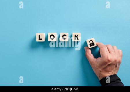 Male hand puts the wooden cube with padlock icon with the word lock. Privacy, security, protection and safety concepts. Stock Photo