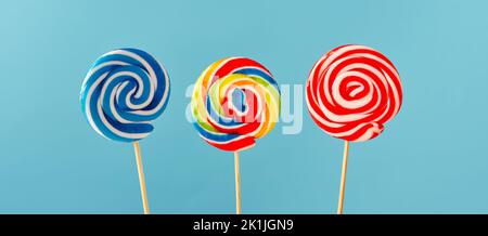 Colorful swirl round candy lollipops on blue background. Stock Photo