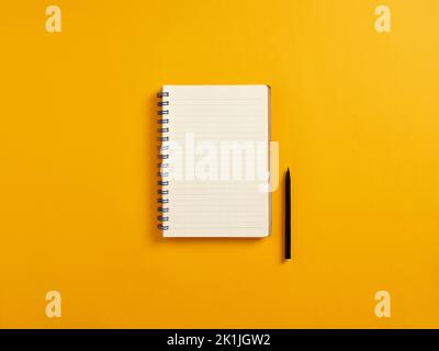 Blank or empty notepad and black pen on yellow background with copy space. Stock Photo