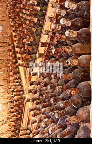Old wine cellar with wooden beams and dozens of old, dusty bottles of wine, maturing peacefully in a cellar somewhere in Zakynthos island, Greece.