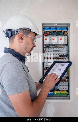 Electrical technician looking focused while working in a switchboard with fuses. Stock Photo