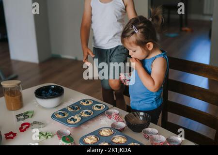 Happy family with two children making and decorating cupcakes with chocolate and berries at home kitchen. Sweets cupcake cake. Happy family. Sweet Stock Photo