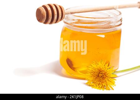 Honey dripping from honey dipper in glass jar with dandelion. Healthy food concept. Stock Photo