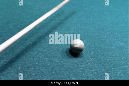 Cue ball on a worn out old pool table. A game of pool with used equipment. Stock Photo