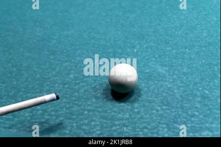 Cue ball on a worn out old pool table. A game of pool with used equipment. Stock Photo