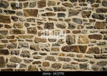 View of old wall built with stones in warm tones. Concept for backgrounds and textures. Stock Photo