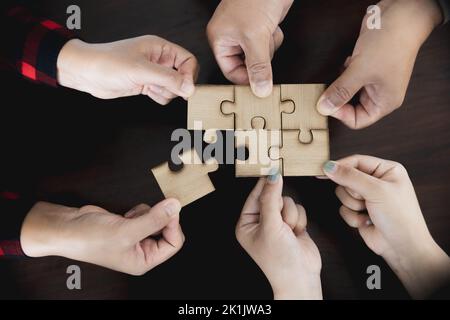 Hands of diverse people assembling jigsaw puzzle, team put pieces together searching for right match, help support in teamwork to find common solution Stock Photo