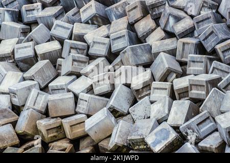 Concrete blocks piled form a breakwater and cover the entire frame Stock Photo