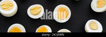 Top view of cut boiled eggs with yolks on black background, banner Stock Photo