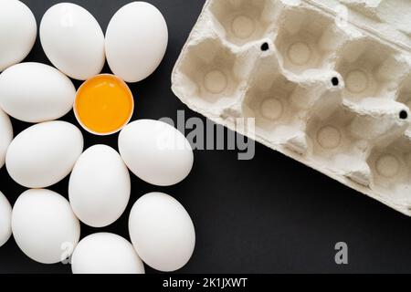 Top view of carton tray near white chicken eggs on black background Stock Photo