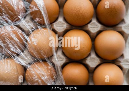 Top view of cellophane on brown chicken eggs in container Stock Photo