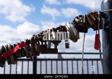 A closeup view of a number of metal locks on a chain dockside in the background Stock Photo