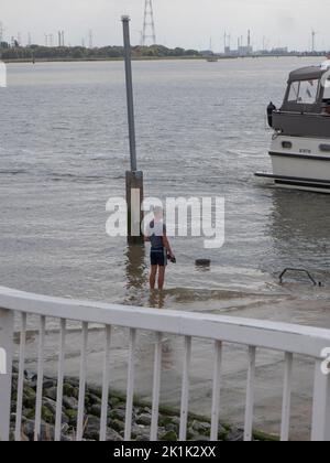 Doel, Belgium, 21 August 2022, Man stands with his feet in the water at the quay Stock Photo