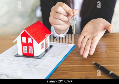Your new house, real estate agent holding house key to his client after signing contract agreement in office,concept for real estate, renting property Stock Photo