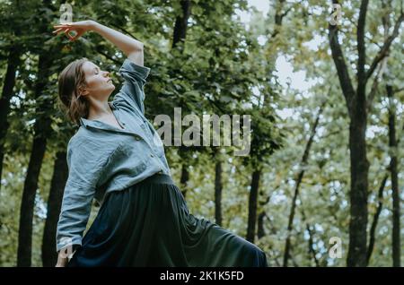 Woman doing yoga peaceful warrior pose with forest trees background Stock Photo