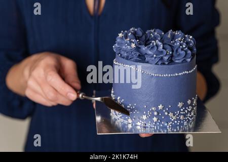 Confectioner is leveling cake with spatula and cake scraper. Stock Photo