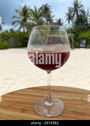 A glass of Sangria served on the beach in a long stem wine glass on an island in the Maldives. Selective focus on the glass. Stock Photo