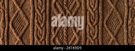 Knitted brown background banner. Large knitted fabric with a pattern. Close-up of a knitted blanket Stock Photo