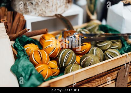 Christmas fair market in Europe. Spices and fruit compositions. Cinnamon sticks, whole dried oranges and limes for wreath decoration in wooden box. Se Stock Photo