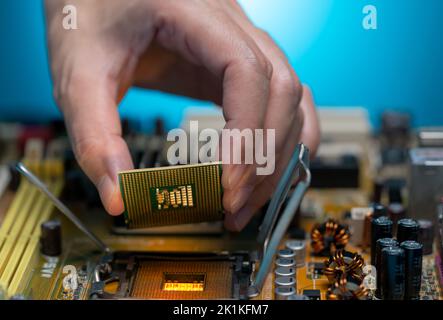 Electronic engineer hand putting computer chip on socket. Chipset on electronic circuit board of PC mother board. CPU chip. Electronic components. Stock Photo