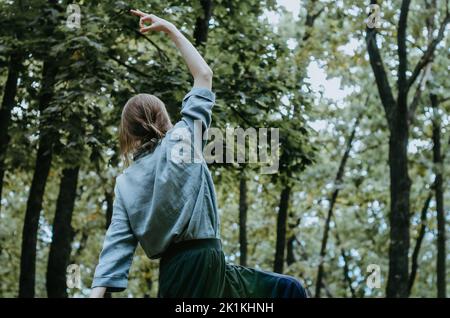 Woman doing yoga peaceful warrior pose in early autumn forest Stock Photo