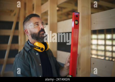 Carpenter checking wooden planks with spirit level, diy eco-friendly homes concept. Stock Photo
