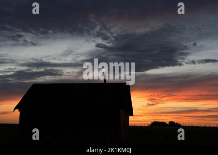 An old rustic farm building silhouette on the Alberta prairies at sunrise in Rocky View County Canada Stock Photo