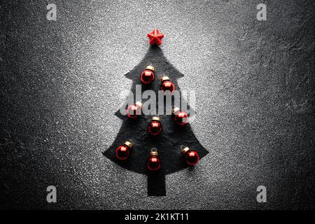 Decorated Christmas tree with red christmas balls and star on top created from artificial snow on black background. Winter holidays concept Stock Photo
