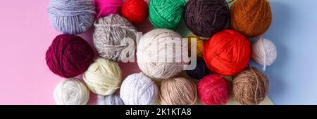 Banner made of balls of knitting threads on a pink and blue background of knitting balls of red, blue, white, green, brown, burgundy. Stock Photo