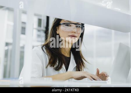 Close up portrait of female researcher, medical scientist or doctor working  on laptop in laboratory Stock Photo