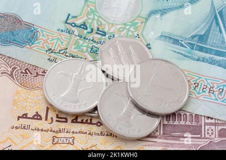 close up of United Arab Emirates dirham coins lying on banknotes Stock Photo