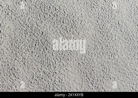 Texture smooth layer of gray neutral sand with traces of drops after severe rainfall with copy space. Texture of Wet sea fine sand on tropical beach a Stock Photo