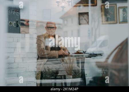 Elegant senior man sitting in a cafe and looking at camera. Stock Photo