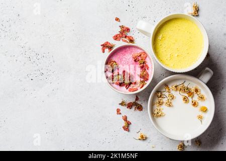 Different types of moon milk: rose flower, golden turmeric and chamomile in white cups, top view. Ayurveda drink, healthy lifestyle, remedy for insomn Stock Photo