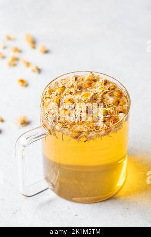 Chamomile tea with flowers in a glass cup. Healthy herbal drink, natural antiseptic and aid in digestion. Stock Photo