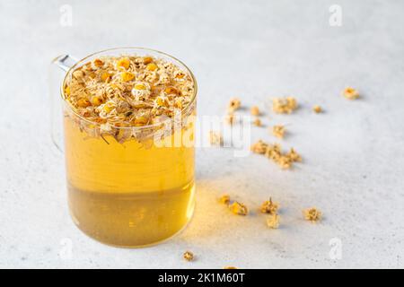 Chamomile tea with flowers in a glass cup. Healthy herbal drink, natural antiseptic and aid in digestion. Stock Photo