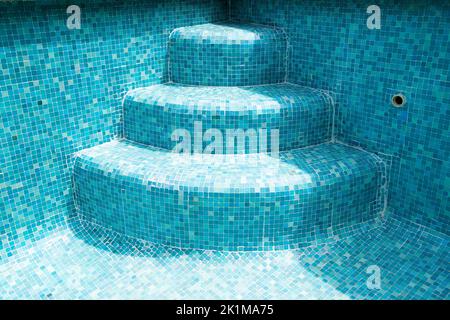 Pool steps in an empty mosaic swimming pool Stock Photo