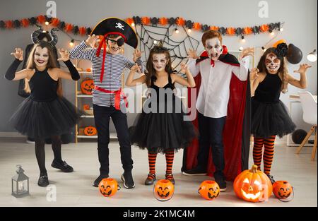 Group of happy children dressed up in spooky costumes having fun at Halloween party Stock Photo