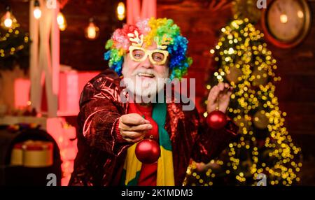 put it on tree. xmas gifts. Time for presents. new year weekend. Fanily holiday. party man in clown wig. happy man with beard. mature bearded freak Stock Photo