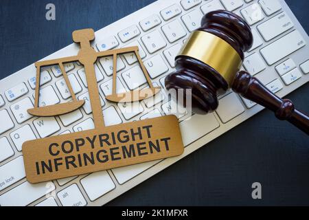 Copyright infringement phrase on the plate, keyboard and gavel. Stock Photo