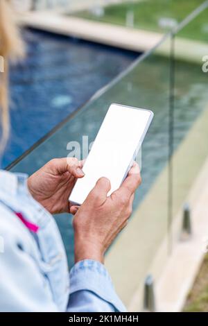 Woman using mobile phone by the pool, empty white screen mockup. Close up. Stock Photo