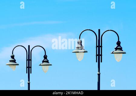 Old-fashioned street lights with broken glass, vintage street lamps close-up against a blue sky on a sunny day Stock Photo