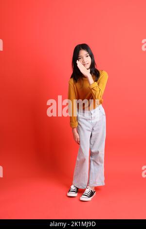 The young Asian girl with yellow shirt on the orange background. Stock Photo