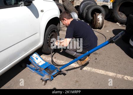 Young man worker changing a tyre on the wheel of a car in Llandovery Wales Carmarthenshire UK   KATHY DEWITT Stock Photo