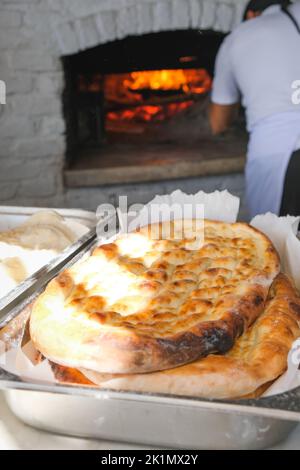 traditional bread in a Turkish bakery during the Ramadan period - Ramazan pidesi, in a stone oven, vertical image. Stock Photo