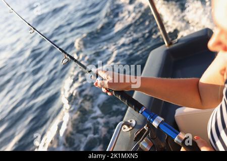 Waiting for catching fish man hand holds a fishing rod with fishing line while sitting in a boat Stock Photo