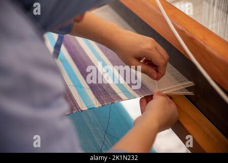 Carpet weaving using traditional techniques on a loom. , close-up of weaving and handmade carpet production. Stock Photo