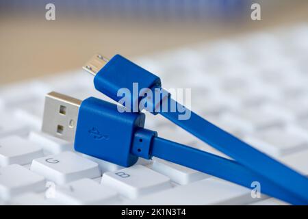 Close-up on a micro USB cable with a white keyboard in the background Stock Photo