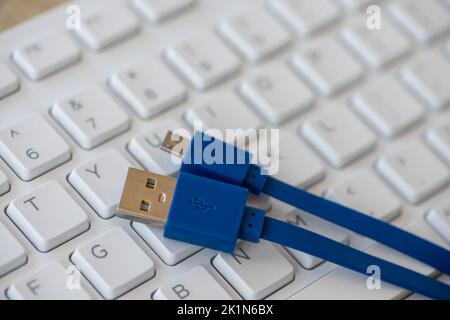 Close-up on a micro USB cable with a white keyboard in the background Stock Photo
